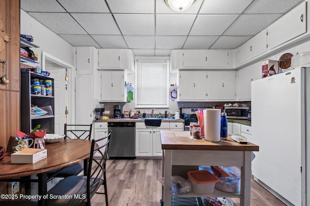 kitchen featuring stainless steel appliances, light countertops, light wood-style flooring, white cabinetry, and a sink