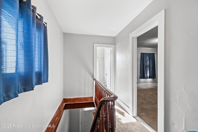 hall featuring carpet floors, an upstairs landing, and baseboards