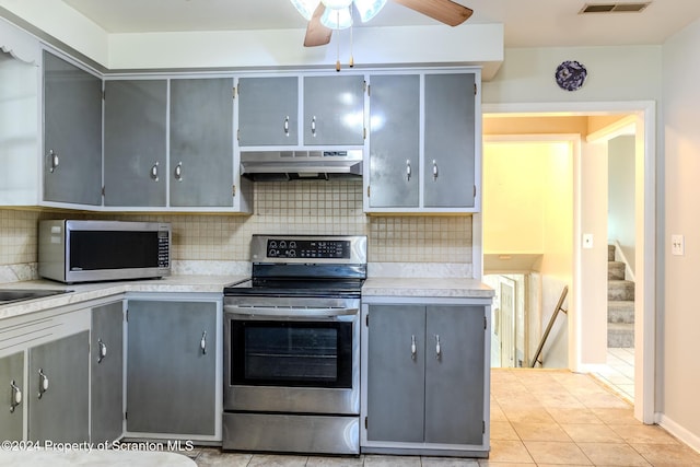 kitchen featuring tasteful backsplash, gray cabinetry, light tile patterned flooring, and stainless steel appliances