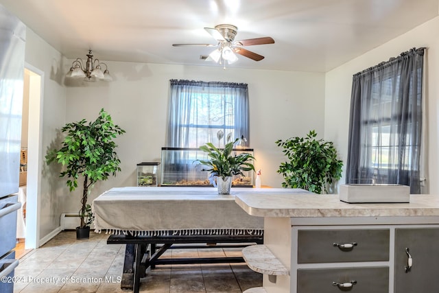 dining space featuring tile patterned floors, ceiling fan with notable chandelier, and a baseboard radiator