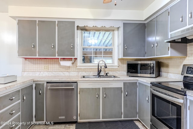 kitchen featuring gray cabinetry, extractor fan, sink, and appliances with stainless steel finishes