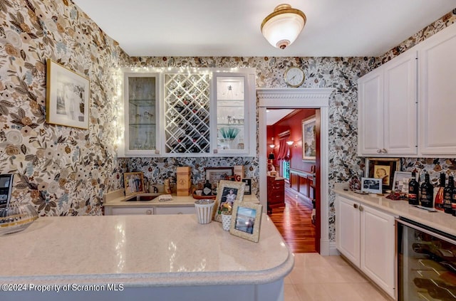 kitchen featuring white cabinetry, sink, light tile patterned floors, and beverage cooler