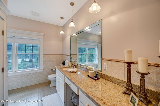 bathroom featuring tile patterned floors, vanity, tile walls, toilet, and lofted ceiling