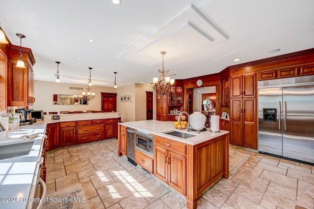 kitchen with built in appliances, pendant lighting, and an island with sink