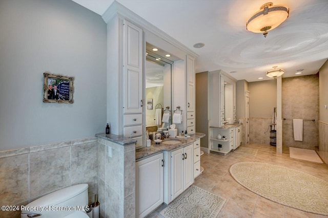 bathroom with vanity, toilet, and tile walls