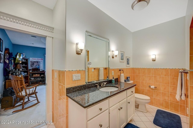 bathroom featuring tile patterned flooring, vanity, toilet, and tile walls