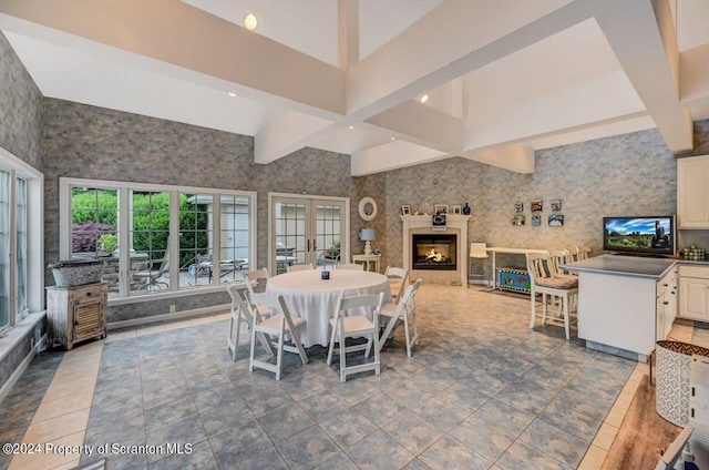 tiled dining room with beam ceiling, a towering ceiling, and french doors