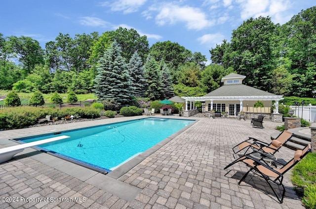 view of pool with a patio and a diving board