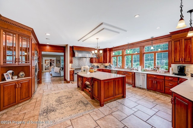 kitchen with pendant lighting, a center island, wall chimney range hood, and stainless steel appliances