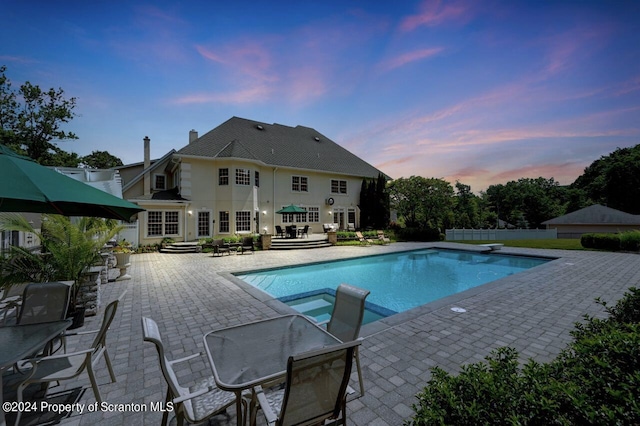 pool at dusk with a diving board, a patio, and french doors