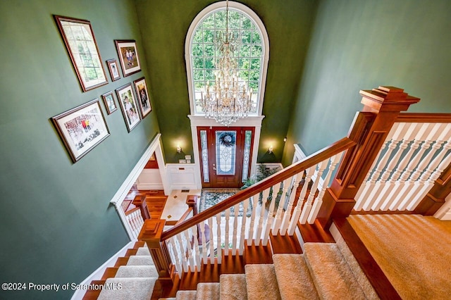 stairway with a towering ceiling and a notable chandelier