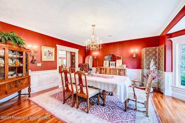 dining room with light wood-type flooring, crown molding, and an inviting chandelier