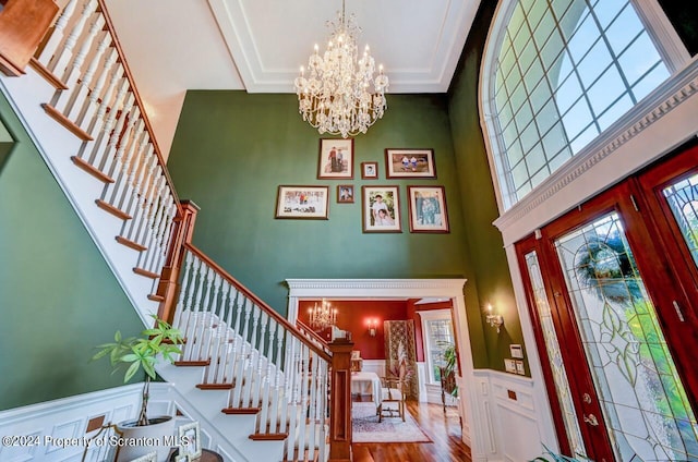 foyer featuring a wealth of natural light, hardwood / wood-style floors, a towering ceiling, and a chandelier