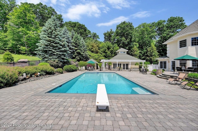 view of pool featuring a diving board, an outdoor structure, and a patio