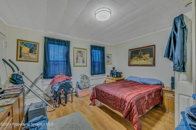 bedroom with ornamental molding and hardwood / wood-style flooring