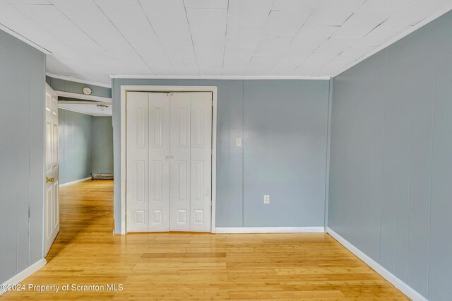 unfurnished bedroom with light hardwood / wood-style flooring, a closet, and ornamental molding