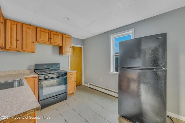 kitchen with a drop ceiling, black appliances, a baseboard radiator, and sink