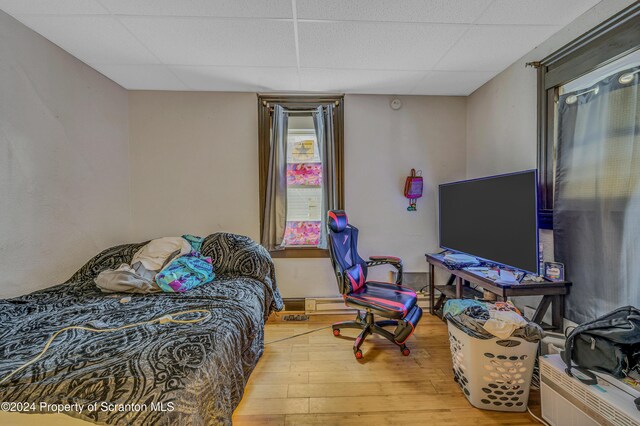 bedroom with hardwood / wood-style floors and a paneled ceiling