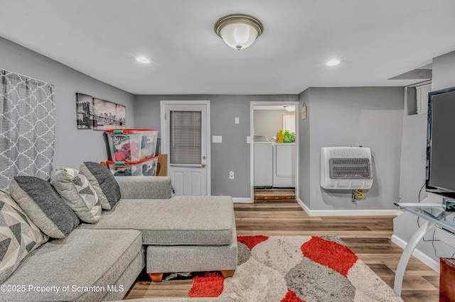 living room featuring heating unit, hardwood / wood-style floors, and independent washer and dryer