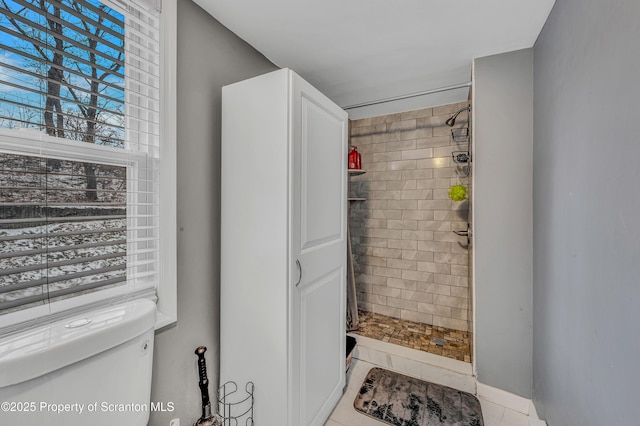 bathroom featuring a tile shower and toilet