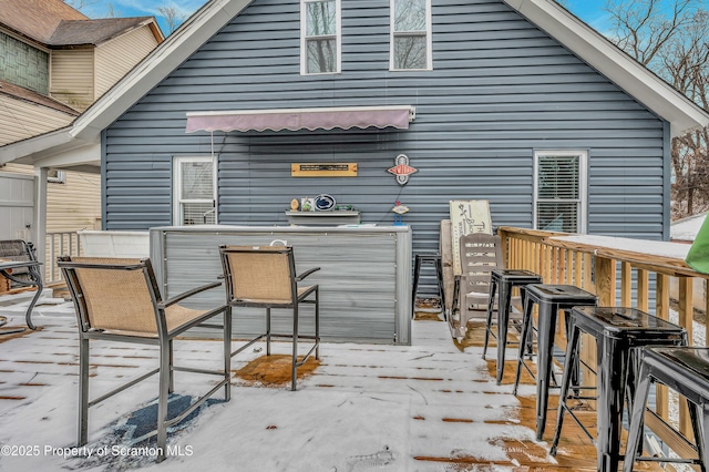 snow covered rear of property featuring an outdoor bar