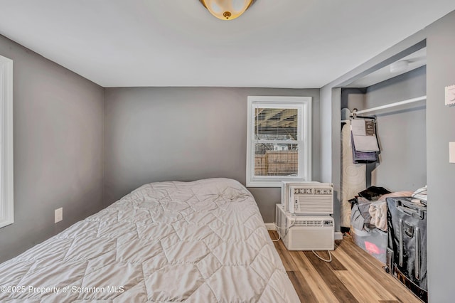 bedroom with a wall mounted air conditioner and light hardwood / wood-style flooring