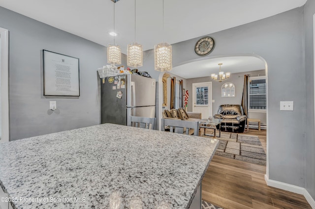 kitchen featuring stainless steel refrigerator, a center island, hardwood / wood-style floors, and pendant lighting