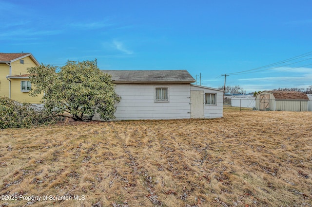 rear view of property featuring a storage shed, an outbuilding, and fence