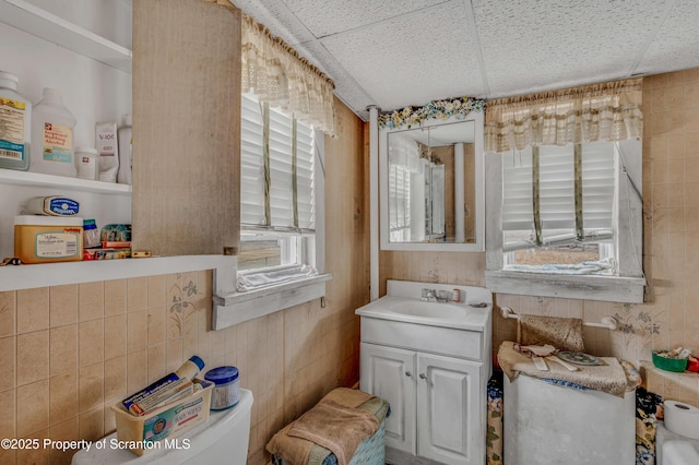 bathroom featuring a paneled ceiling, a healthy amount of sunlight, and vanity