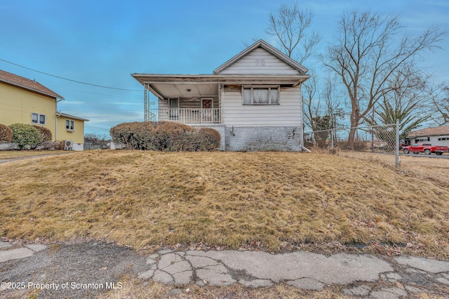 view of front of home with covered porch, a front lawn, and fence