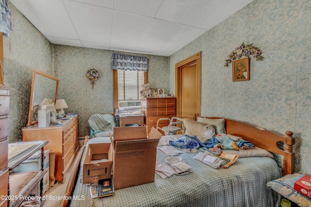 bedroom featuring a paneled ceiling and wallpapered walls