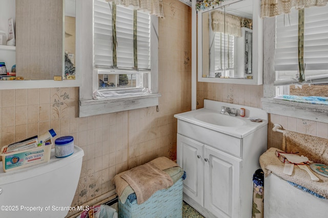 bathroom with tile walls, toilet, and vanity