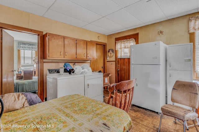 interior space with washer and dryer, freestanding refrigerator, a closet, and a drop ceiling