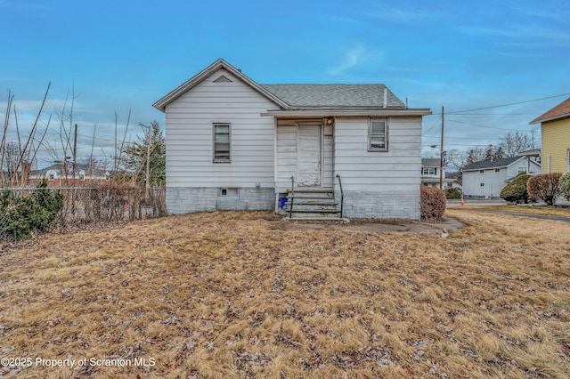 rear view of property with entry steps, crawl space, roof with shingles, and fence