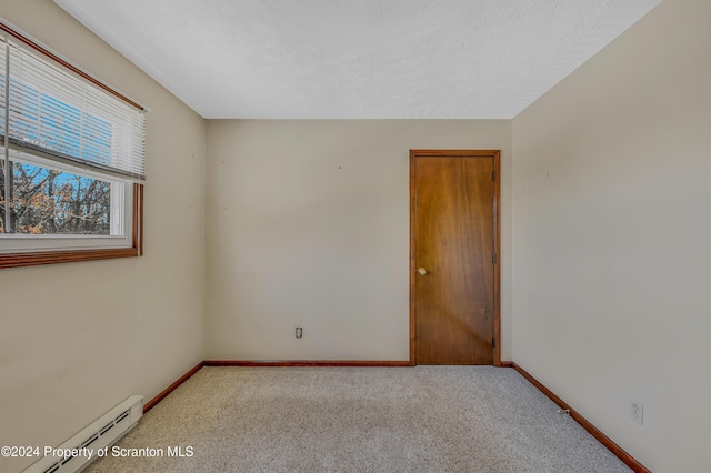 unfurnished room featuring light carpet, a baseboard radiator, and a textured ceiling