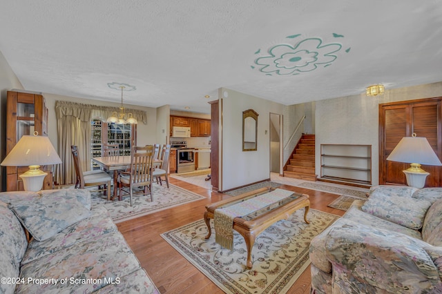 living room with a chandelier, a textured ceiling, and light hardwood / wood-style flooring