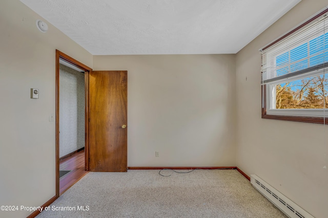 empty room featuring carpet flooring, a textured ceiling, and a baseboard heating unit