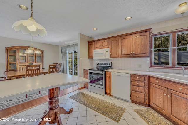 kitchen with white appliances, sink, decorative backsplash, light tile patterned floors, and decorative light fixtures