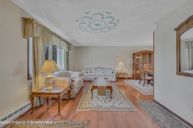 living room featuring a textured ceiling, light hardwood / wood-style flooring, and baseboard heating