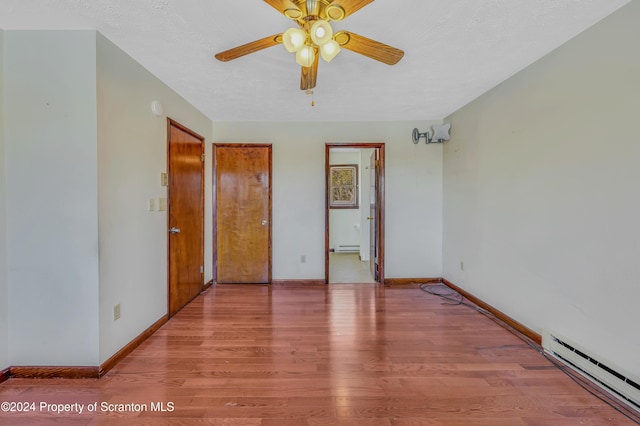 unfurnished bedroom featuring baseboard heating, ceiling fan, light hardwood / wood-style floors, and a textured ceiling