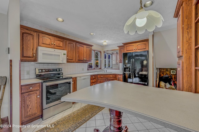 kitchen featuring backsplash, white appliances, a textured ceiling, pendant lighting, and light tile patterned floors