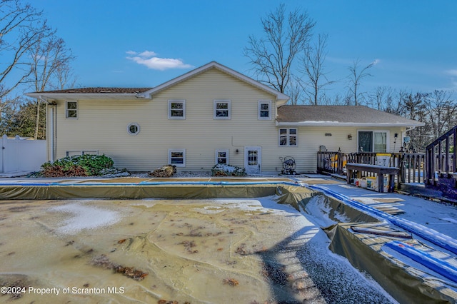 snow covered rear of property with a covered pool