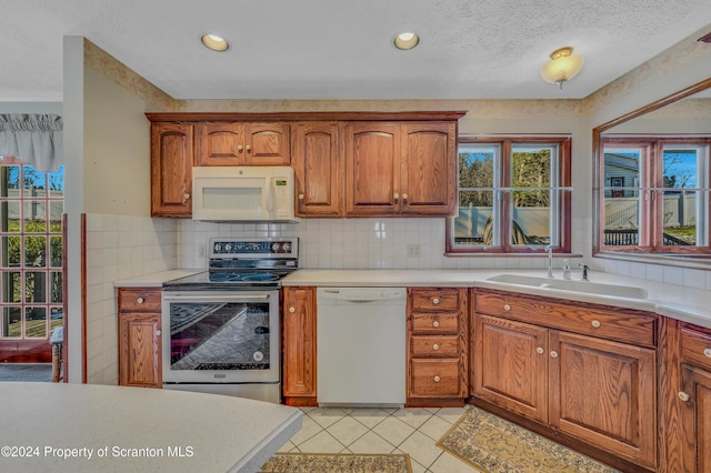 kitchen featuring white appliances, sink, light tile patterned floors, and tasteful backsplash