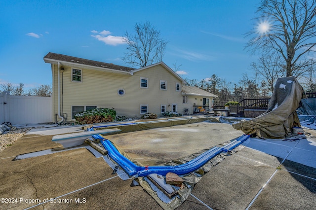 rear view of property featuring a patio and a covered pool