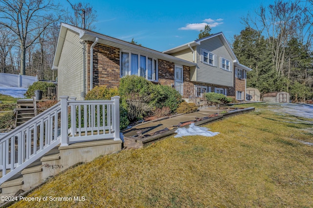 tri-level home featuring a storage unit and a front yard