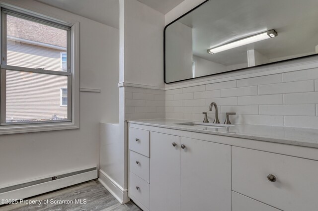 326 Neptune Pl, Scranton, PA 18505 - bathroom with a baseboard heating unit, decorative backsplash, vanity, and wood finished floors
