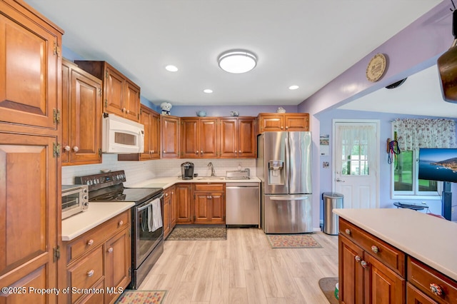 592 Gravel Pond Rd, Clarks Summit, PA 18411 - kitchen with appliances with stainless steel finishes, light wood-style floors, light countertops, brown cabinetry, and backsplash