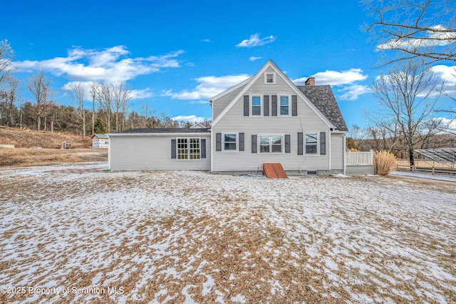 snow covered back of property featuring a chimney and roof with shingles