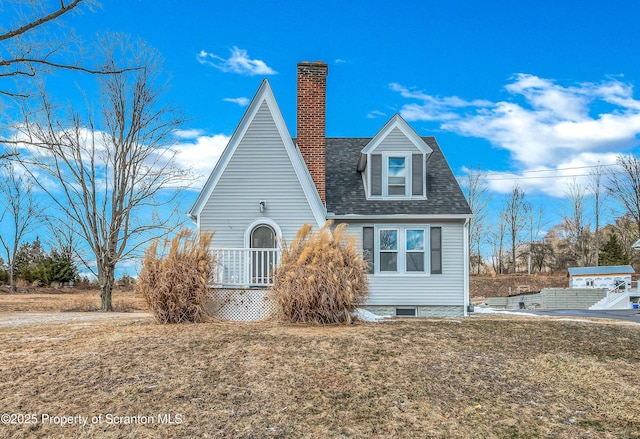 view of side of home featuring a shingled roof, a chimney, and a yard