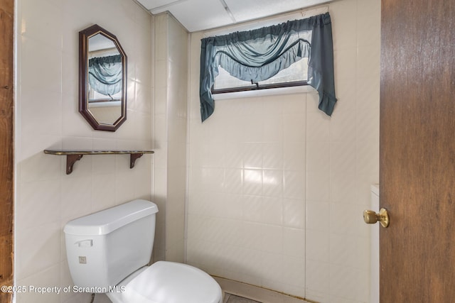 bathroom with toilet and tile walls